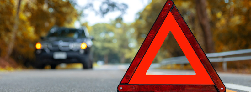 A roadside sign with a car approaching in the distance, representing Hollard Seguros Roadside and Legal Assist